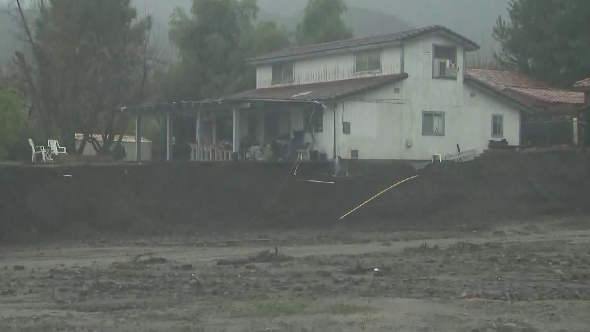 A home sits precariously on an eroded hillside near a rain-swollen creek in Lake Elsinore on Feb. 14, 2019. (Credit: KTLA)