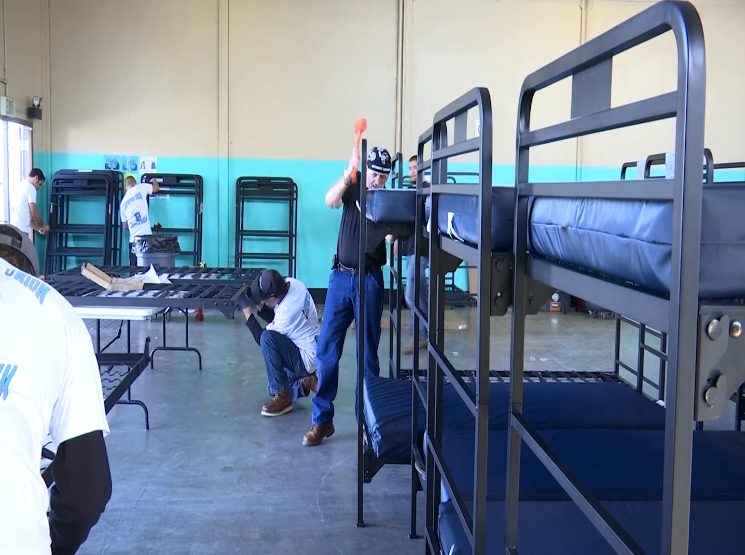 Volunteers work to put together beds funded by donations from weed dispensaries at a temporary homeless shelter in Oxnard on Feb. 25, 2019. (Credit: KEYT)