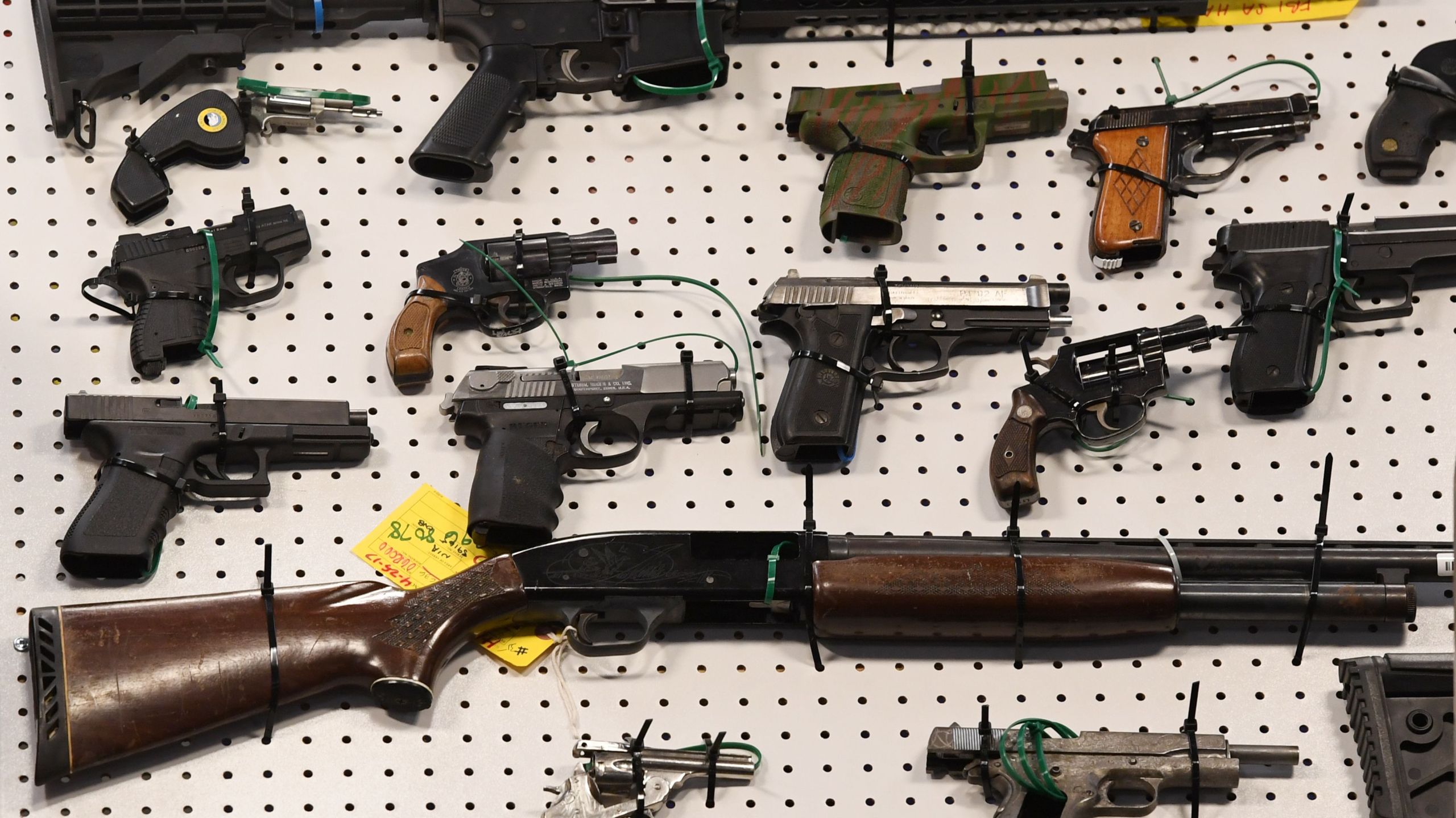 Representatives from the FBI and Los Angeles Police Department display weapons seized after a raid in which three dozen reputed members of street gangs from the San Fernando Valley and South Los Angeles were arrested on Feb. 13, 2019. (Mark Ralston / AFP / Getty Images)