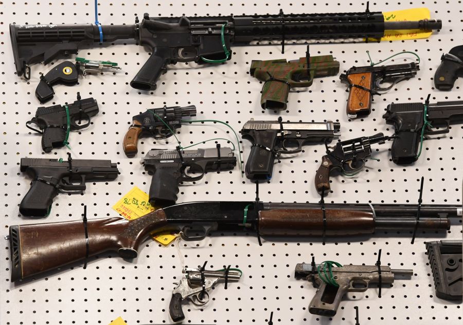 Representatives from the FBI and Los Angeles Police Department display weapons seized after a raid in which three dozen reputed members of street gangs from the San Fernando Valley and South Los Angeles were arrested on Feb. 13, 2019. (Mark Ralston / AFP / Getty Images)