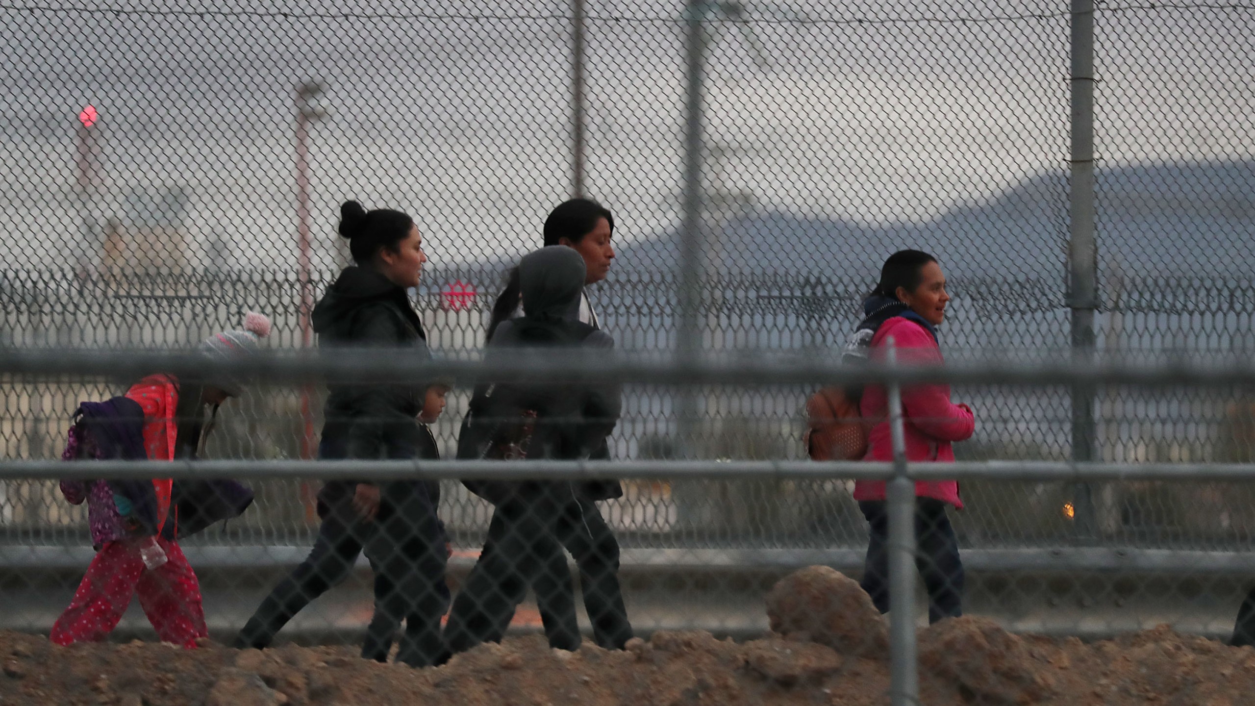 Migrants walk along the U.S.- Mexico border wall as they make their way to U.S. Border Patrol on Feb. 10, 2019 in El Paso, Texas. (Credit: Joe Raedle/Getty Images)