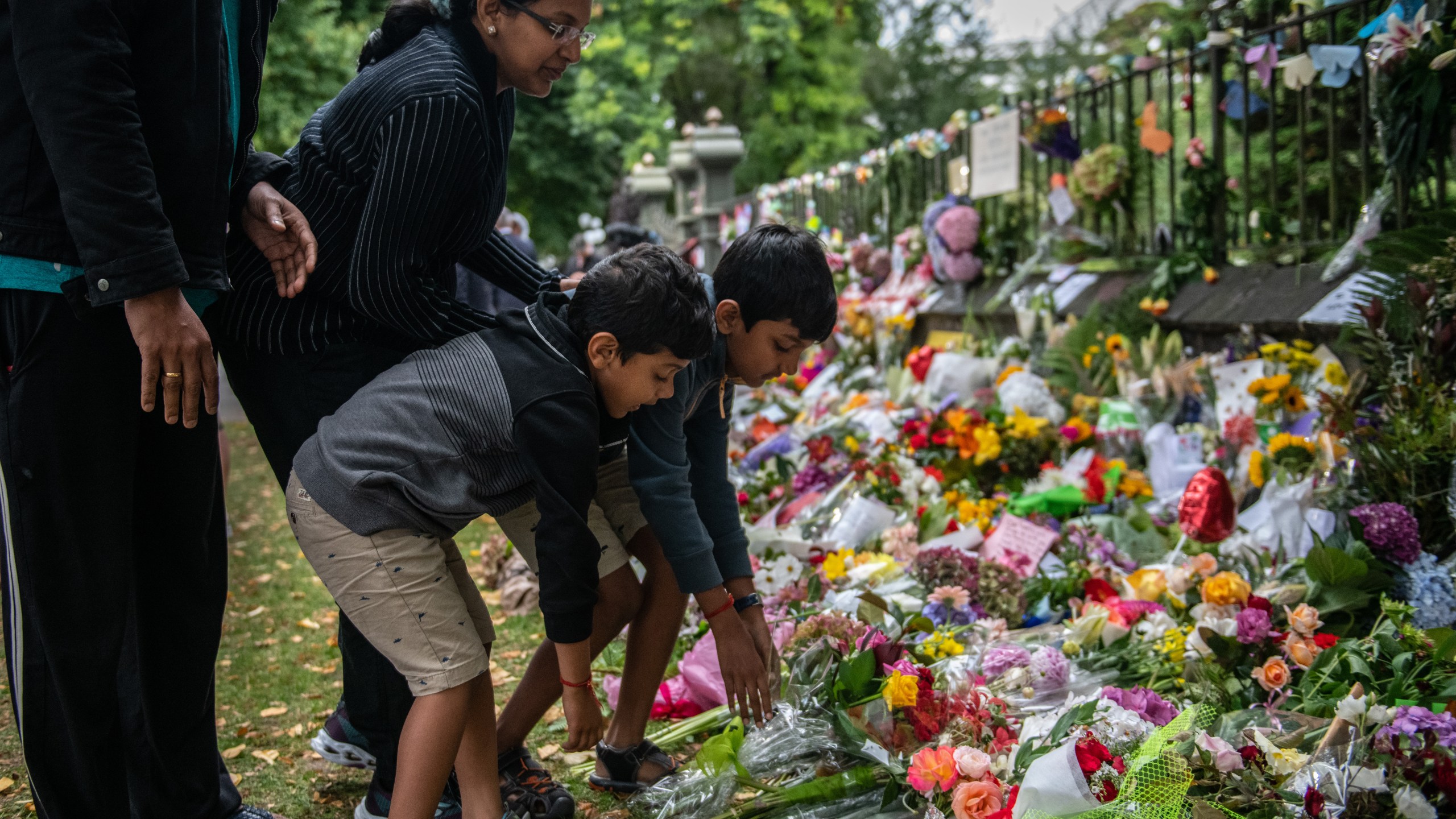 A family lays flowers by the wall of the Botanic Gardens on March 17, 2019, in Christchurch, New Zealand. (Credit: Carl Court/Getty Images)