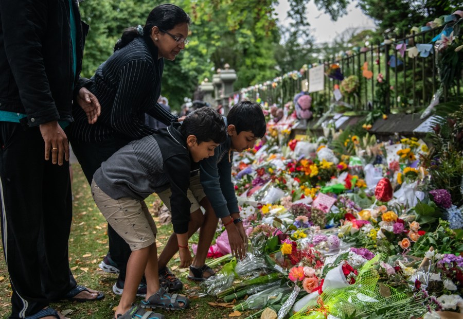 A family lays flowers by the wall of the Botanic Gardens on March 17, 2019, in Christchurch, New Zealand. (Credit: Carl Court/Getty Images)