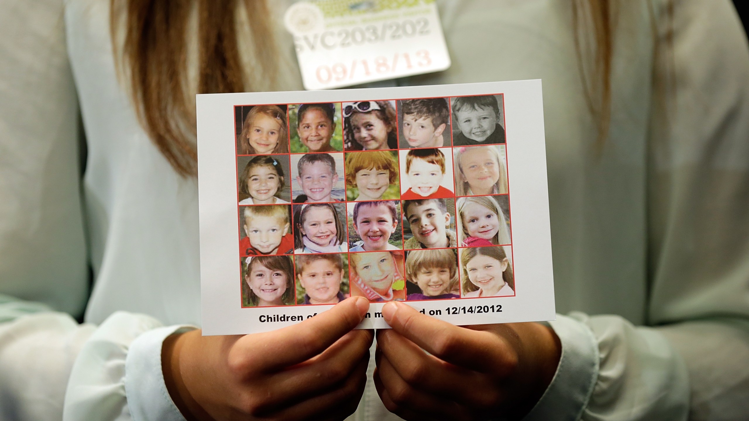 Kyra Murray holds a photo of the victims of the shooting at Sandy Hook Elementary School during a press conference at the U.S. Capitol on Sept. 18, 2013 in Washington, D.C. (Credit: Win McNamee/Getty Images)