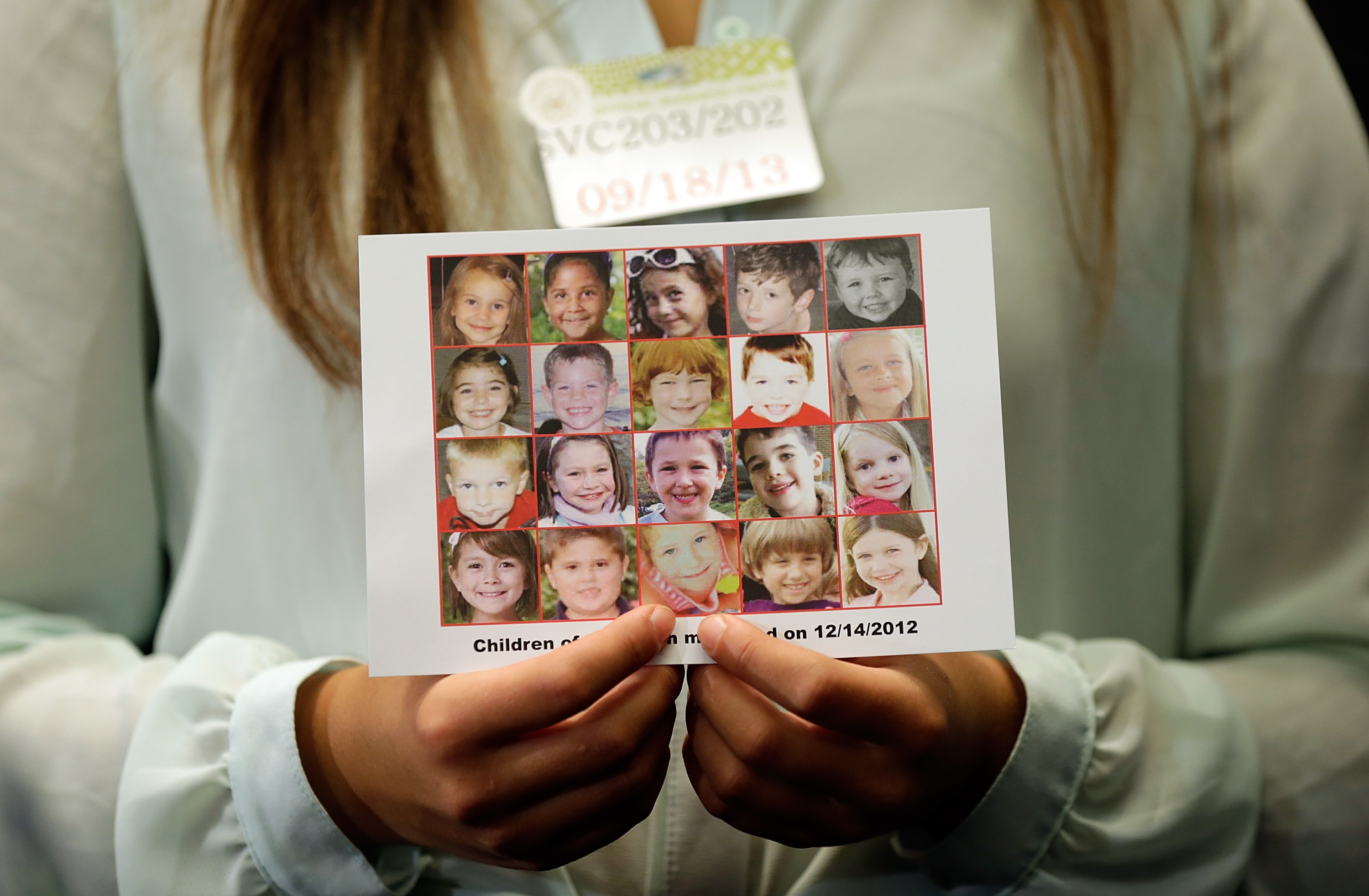 Kyra Murray holds a photo of the victims of the shooting at Sandy Hook Elementary School during a press conference at the U.S. Capitol on Sept. 18, 2013 in Washington, D.C. (Credit: Win McNamee/Getty Images)