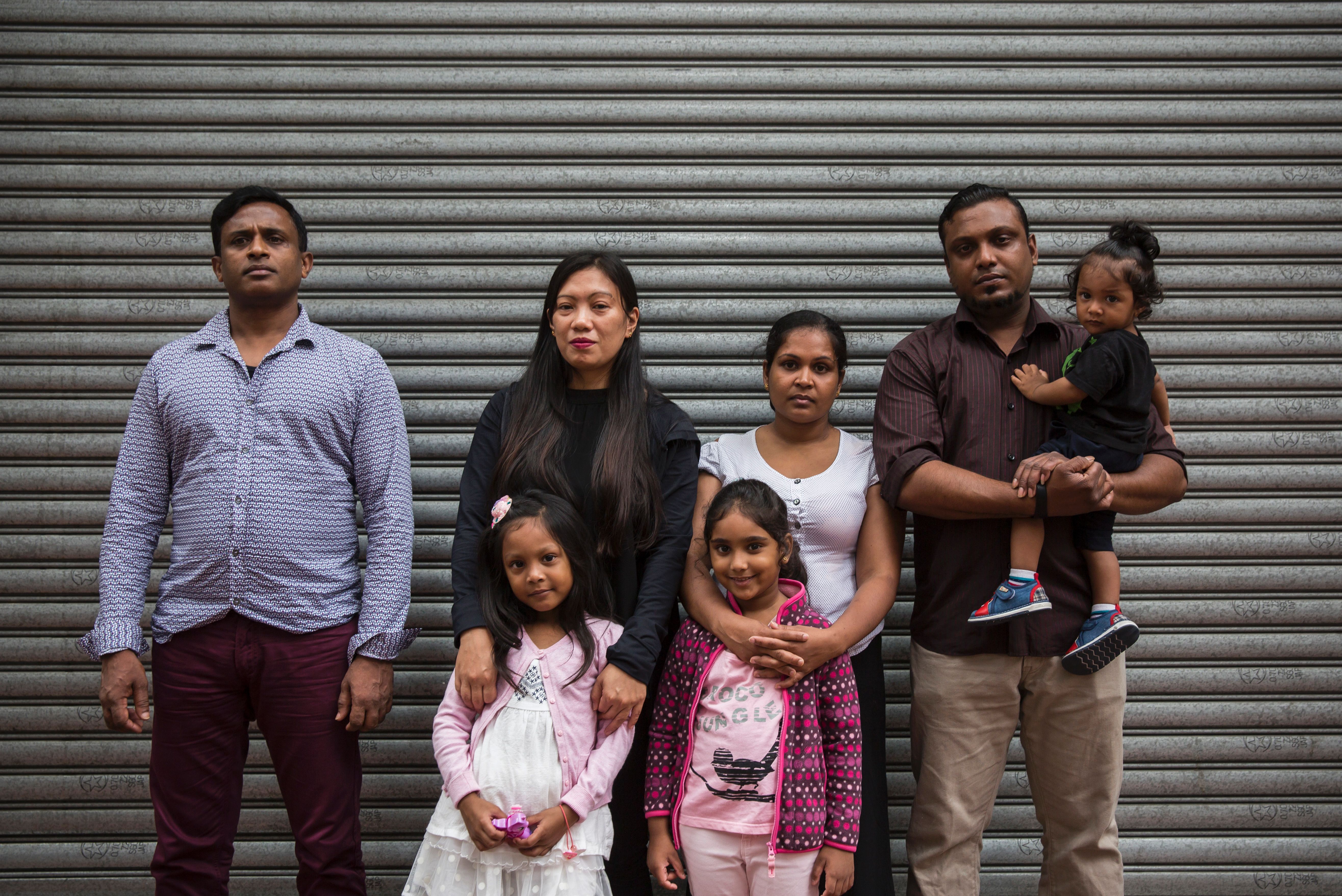 Sri Lankan refugee Ajith Puspa (left), Filipino refugee Vanessa Rodel (second from left) with her daughter Keana, Sri Lankan refugees Nadeeka Nonis (third from right) with her partner Supun Thilina Kellapatha (second from right) and children Sethumdi (fourth from right) and Dinath (right) pose for a photo in front of the Torture Claims Appeal Board building in Hong Kong on July 17, 2017, before attending an appeal hearing over the rejection of their refugee status in the southern Chinese city. (Credit: ISAAC LAWRENCE/AFP/Getty Images)