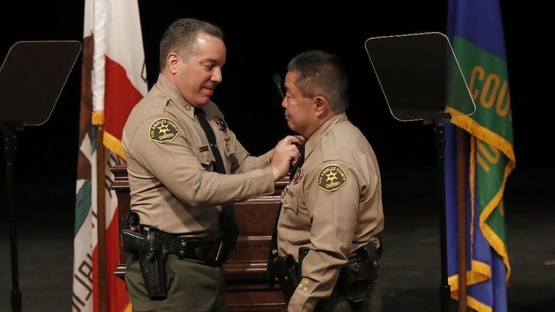 Los Angeles County Sheriff Alex Villanueva, left, places a pin on the collar of Assistant Sheriff Tim Murakami during a ceremony at East Los Angeles College on Dec. 3, 2018. (Mel Melcon / Los Angeles Times)