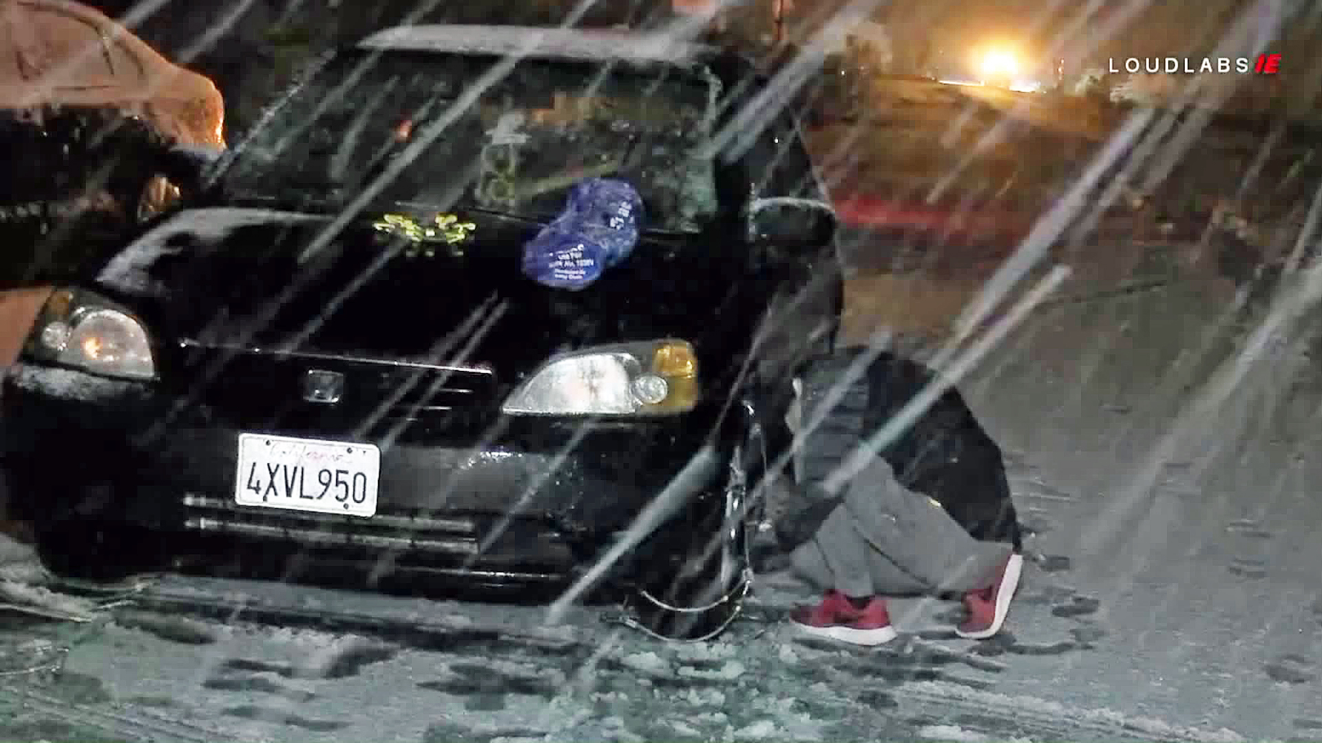 A driver puts chains on his vehicle during a snow storm. (Credit: Loudlabs)