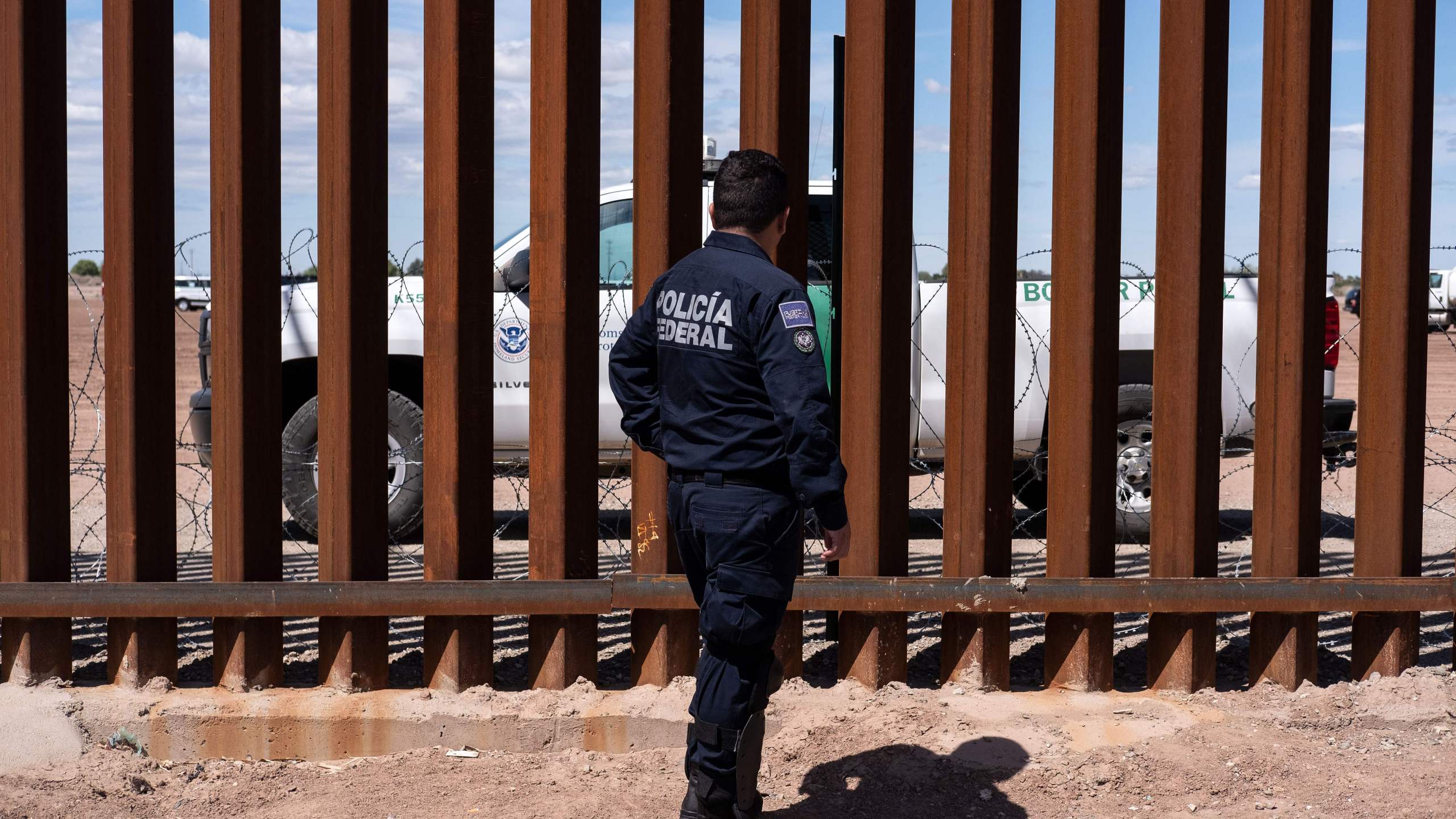 A Border patrol unit and a Mexican federal police guard stop near the U.S.-Mexico border fence in Calexico, California. (Credit: GUILLERMO ARIAS/AFP/Getty Images)