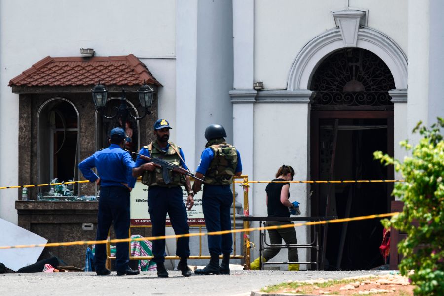 A foreign investigator (R) walks into St. Anthony's Shrine as soldiers stand guard in Colombo on April 25, 2019. (Credit: JEWEL SAMAD/AFP/Getty Images)