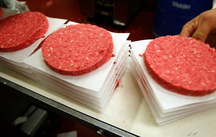 Eliseo Araujo removes ground beef patties from a conveyor belt at Ray's Wholesale Meats December 29, 2003, in Yakima, Washington. (Credit: Justin Sullivan/Getty Images)