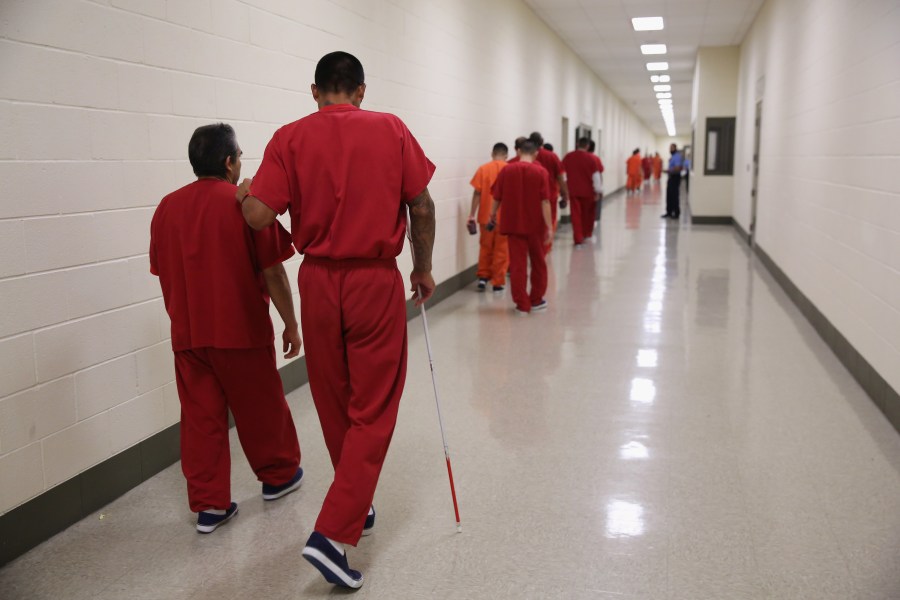 A blind detainee walks with a fellow immigrant at the Adelanto Detention Facility on Nov. 15, 2013 in Adelanto. (Credit: John Moore/Getty Images)