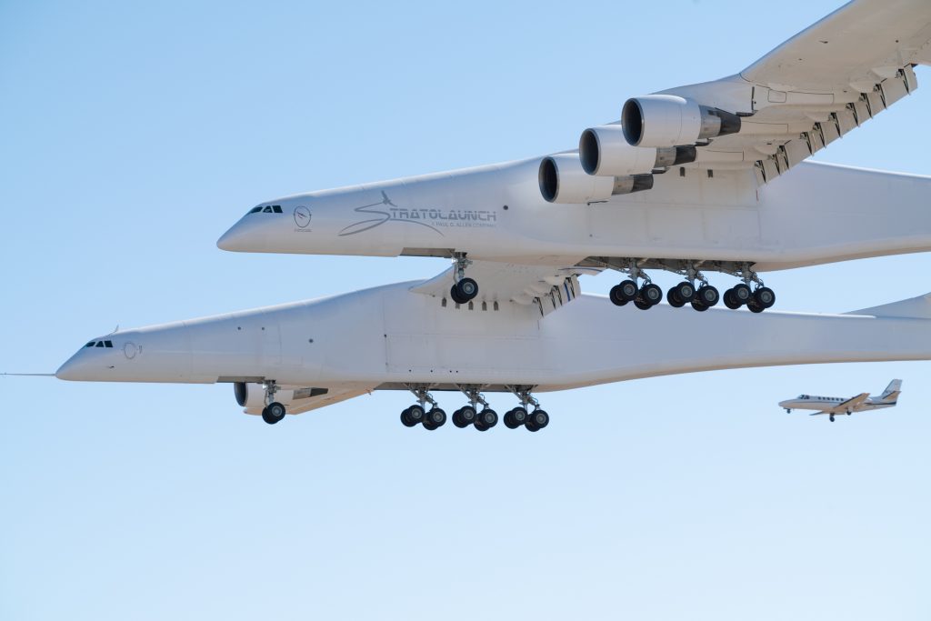 The Stratolaunch, the world's largest plane, flies alongside another aircraft over the Mojave Desert on April 13, 2019. (Credit: Stratolaunch)