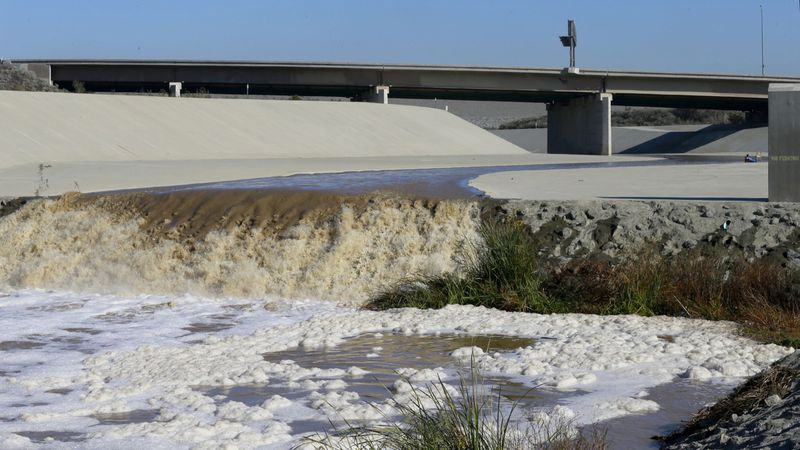 Stormwater flows down the Santa Ana River channel from Prado Dam while hydrologic technicians with the USGS California Water Science Center conduct high-flow velocity and volume measurements. (Credit: Allen J. Schaben / Los Angeles Times)