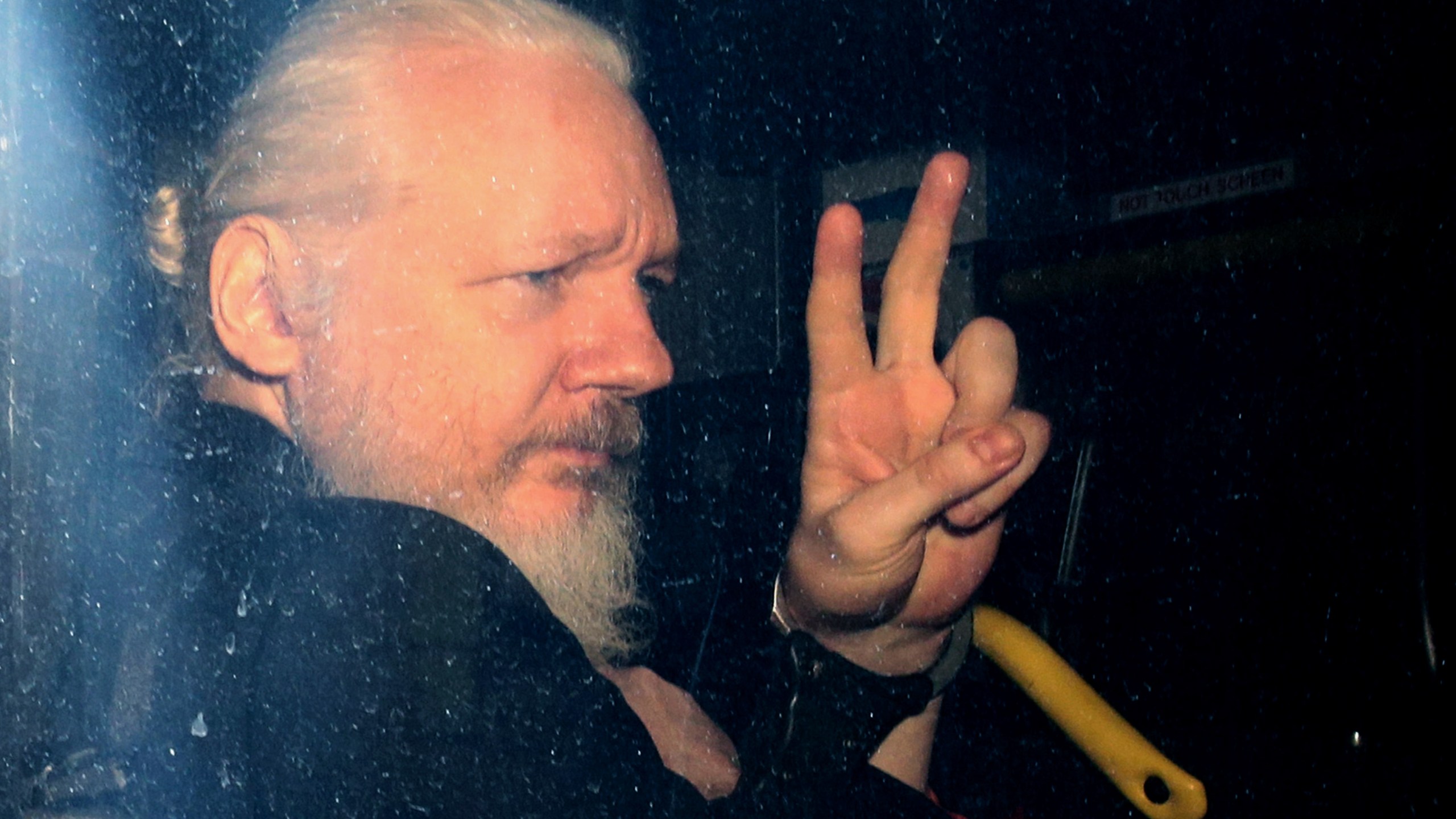 Julian Assange gestures to the media from a police vehicle on his arrival at Westminster Magistrates court on April 11, 2019 in London, England. (Jack Taylor/Getty Images)