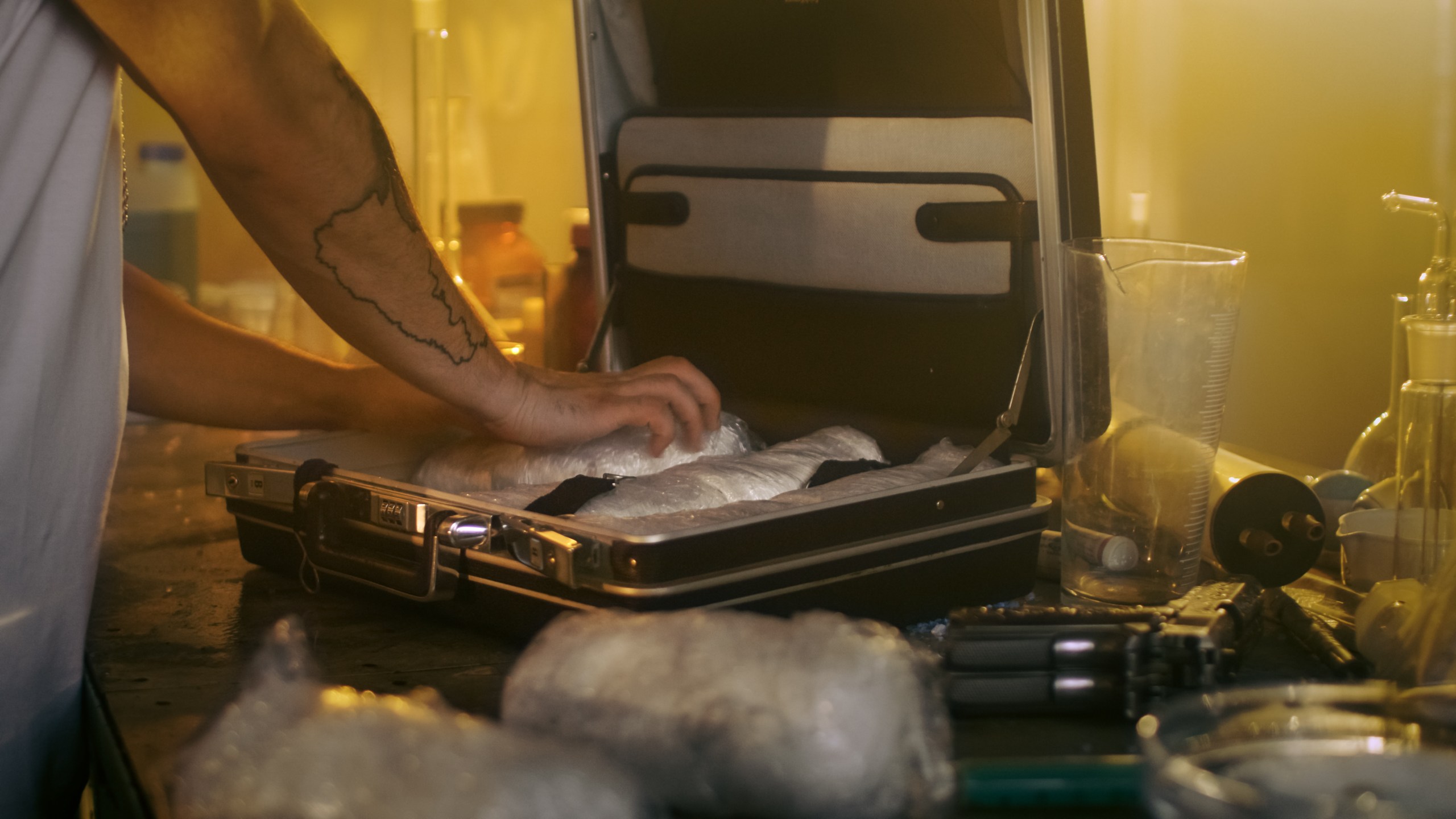 A man places brick packs filled with drugs into a suitcase. (Credit: iStock / Getty Images Plus)