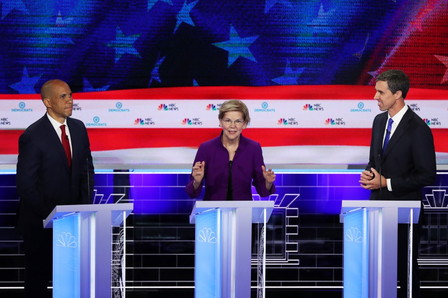 Sen. Elizabeth Warren (D-MA) speaks as Sen. Cory Booker (L) (D-NJ) and former Texas congressman Beto O'Rourke look on during the first night of the Democratic presidential debate on June 26, 2019 in Miami, Florida. (Credit: Joe Raedle/Getty Images)