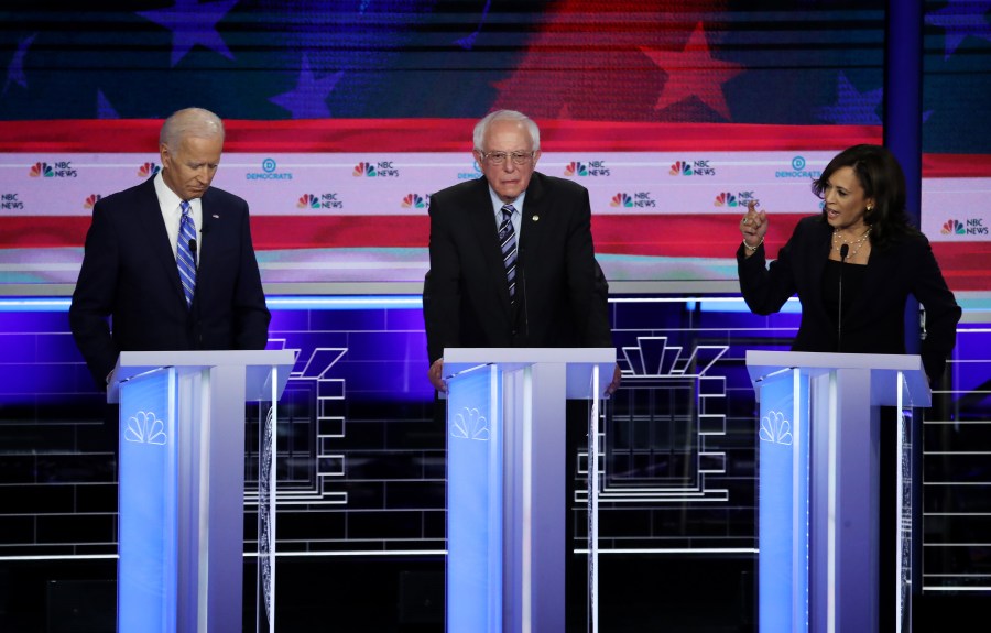 Sen. Kamala Harris, right, and former Vice President Joe Biden, left, speak as Sen. Bernie Sanders looks on during the second night of the first Democratic presidential debate on June 27, 2019, in Miami. (Credit: Drew Angerer / Getty Images)