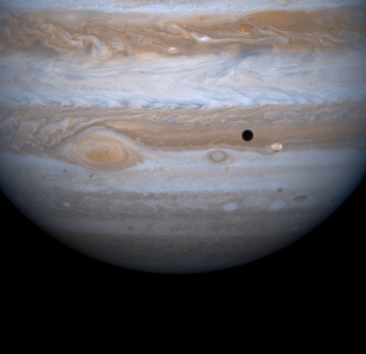 The entire body of Moon-sized Io, as it casts a black shadow, is captured here alongside the planet Jupiter in this picture taken by NASA's Cassini spacecraft, December 3, 2000. (Credit: NASA/Newsmakers)