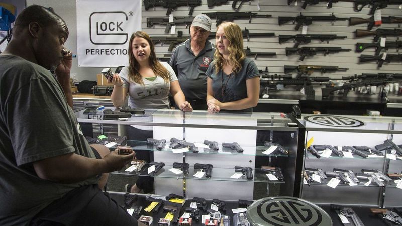 Store managers Jamie Taflinger, left, and Kendyll Murray show customer Cornell Hall different types of ammo at the Get Loaded gun store in Grand Terrace. (Credit: Gina Ferazzi / Los Angeles Times)