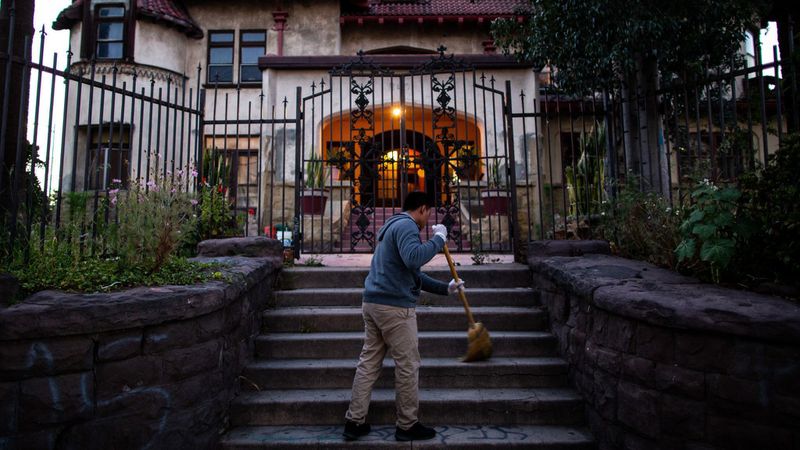 Resident Hildner Coronado Atjun sweeps the front stairs of Casa Libre in May 2019. (Credit: Kent Nishimura / Los Angeles Times)