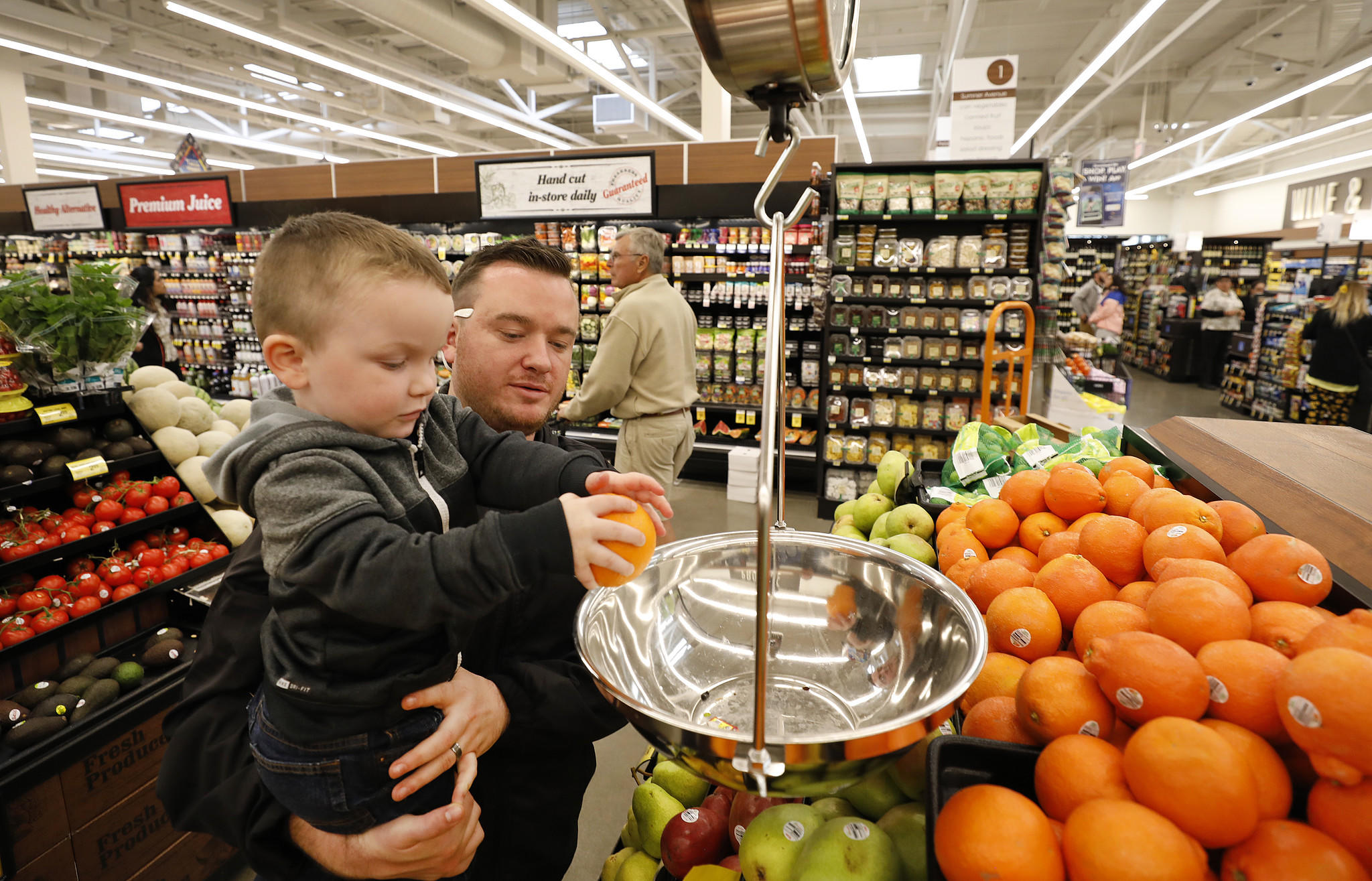 Zachary Reitz, who has vacationed on Catalina Island since he was a child, holds his 3-year-old son Jace Reitz as he weighs fruit at the new Vons Avalon Market on Catalina Island. (Credit: Al Seib / Los Angeles Times)