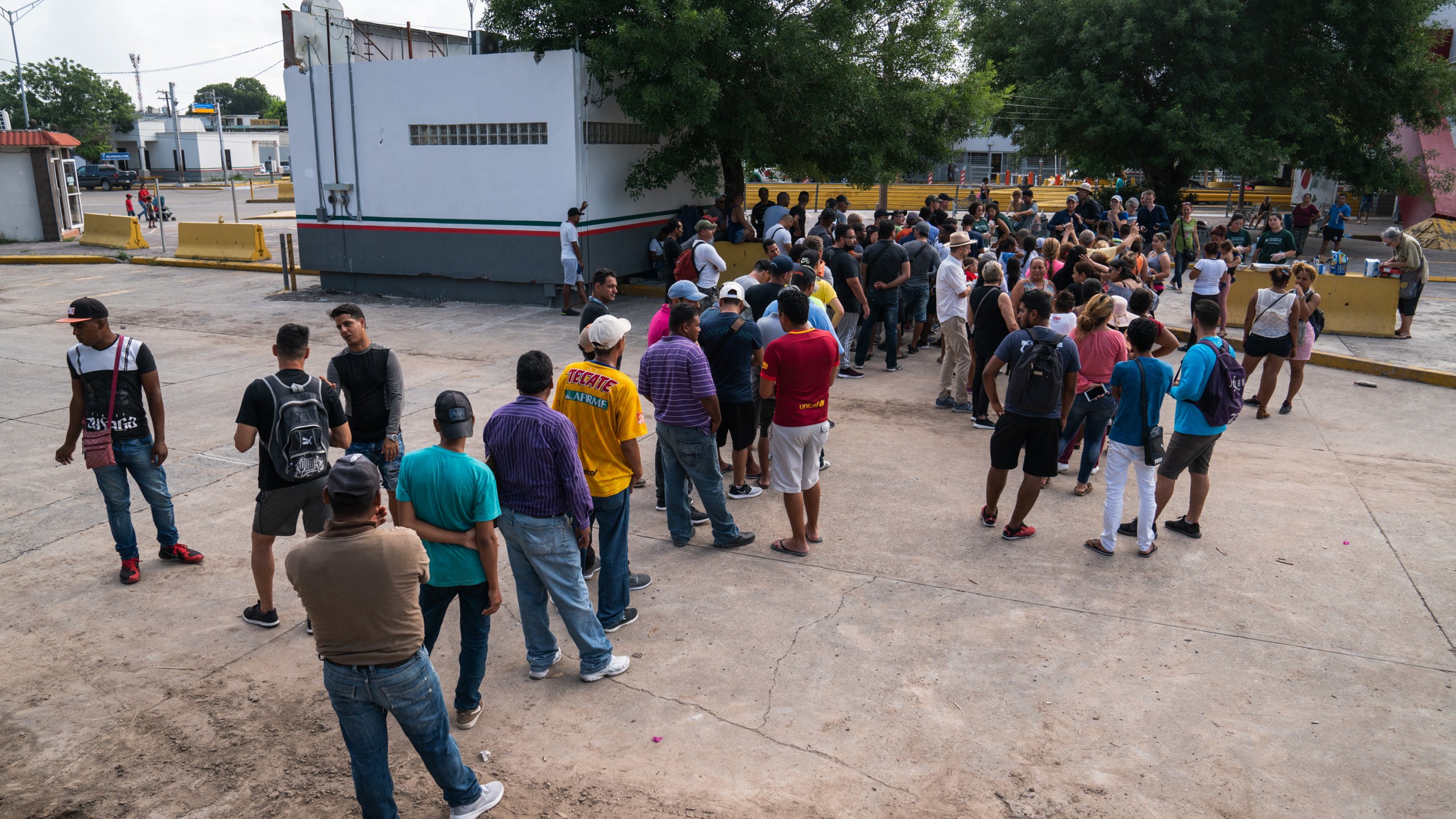 Asylum-seekers wait in line to get a meal close to the International Bridge near a section where a father and daughter drowned attempting to cross into the United States on June 26, 2019 in Matamoros, Tamaulipas. (Credit: Verónica G. Cárdenas/Getty Images)