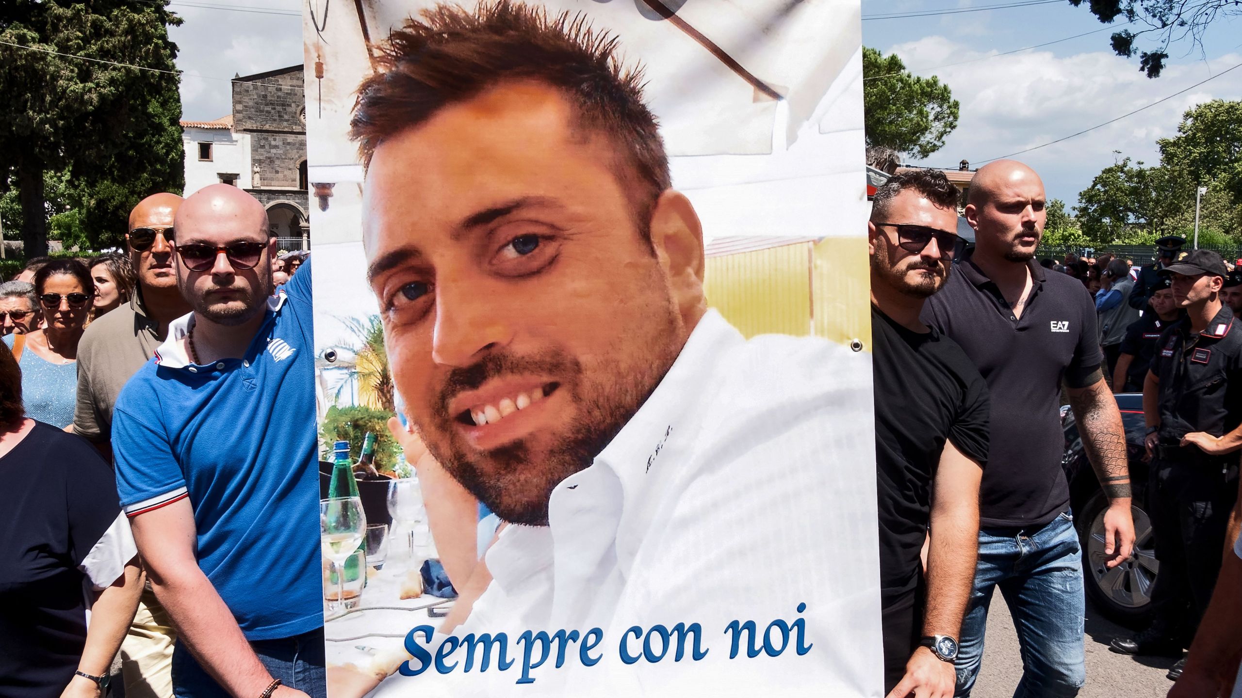 People carry a banner bearing the photo of Carabinieri officer Mario Cerciello Rega and reading "Sempre con noi" ("ever with us") at the end of the funeral mass at Santa Croce church in Somma Vesuviana, near Naples, on July 29, 2019. (Credit: ELIANO IMPERATO/AFP/Getty Images)