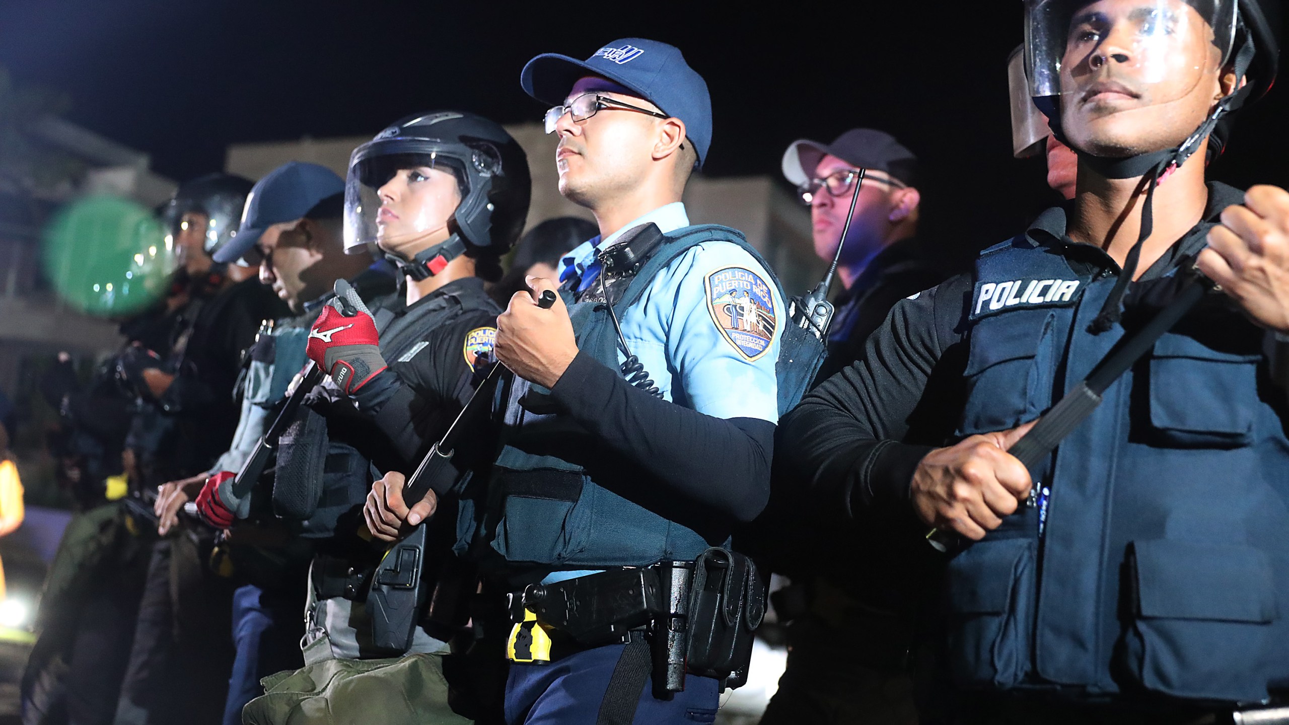 Police officers push back protesters from a parking lot gate to allow politicians to leave after a meeting with Ricardo Rossello, the governor of Puerto Rico, at the Yolanda Guerrero Cultural center on July 21, 2019 in Guaynabo, Puerto Rico. (Credit: Joe Raedle/Getty Images)