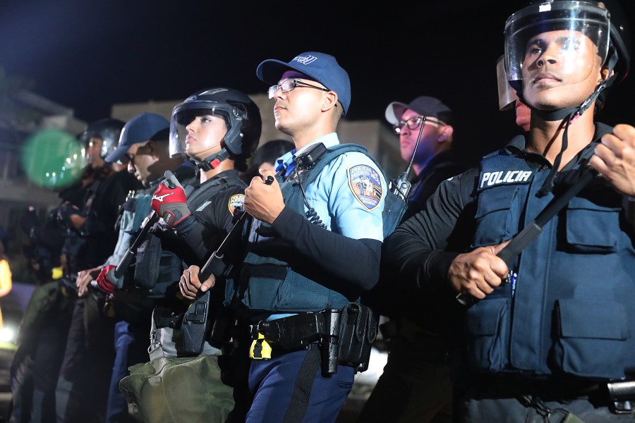 Police officers push back protesters from a parking lot gate to allow politicians to leave after a meeting with Ricardo Rossello, the governor of Puerto Rico, at the Yolanda Guerrero Cultural center on July 21, 2019 in Guaynabo, Puerto Rico. (Credit: Joe Raedle/Getty Images)