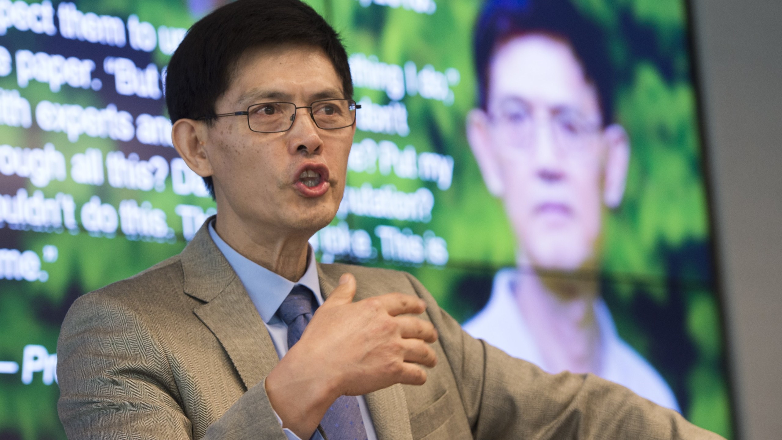 Xiaoxing Xi, chair of the Physics Department at Temple University, speaks alongside a photo of Sherry Chen (right), a U.S. federal government worker, about the dropped charges against them for spying for China, during a press conference in Washington, D.C., Sept. 15, 2015. (Credit: SAUL LOEB/AFP/Getty Images)