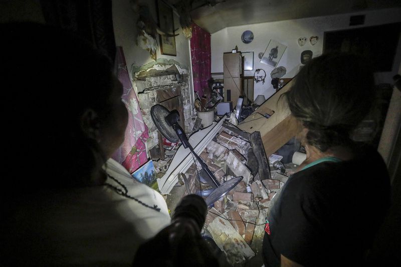 An emergency response team member walks with a Trona resident as she sorts through the rubble of her home on July 6, 2019. (Credit: Robert Gauthier / Los Angeles Times)