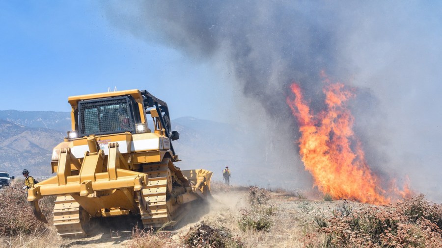 Crews use a bulldozer as they battle a brush fire in San Bernardino on July 31, 2019, in an image released by the San Bernardino County Fire Department.