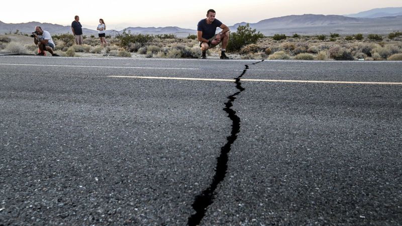 Heath Williamson, from Australia, makes a video of the road cracks along Highway 178 between Ridgecrest and Trona in July 2019. (Credit: Irfan Khan / Los Angeles Times)