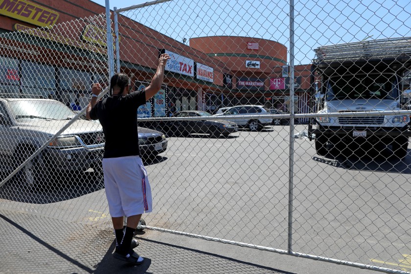 Workers install a fence on Aug. 1, 2019, outside the lot in South Los Angeles where rapper and activist Nipsey Hussle was killed in March.(Credit: Gary Coronado / Los Angeles Times)