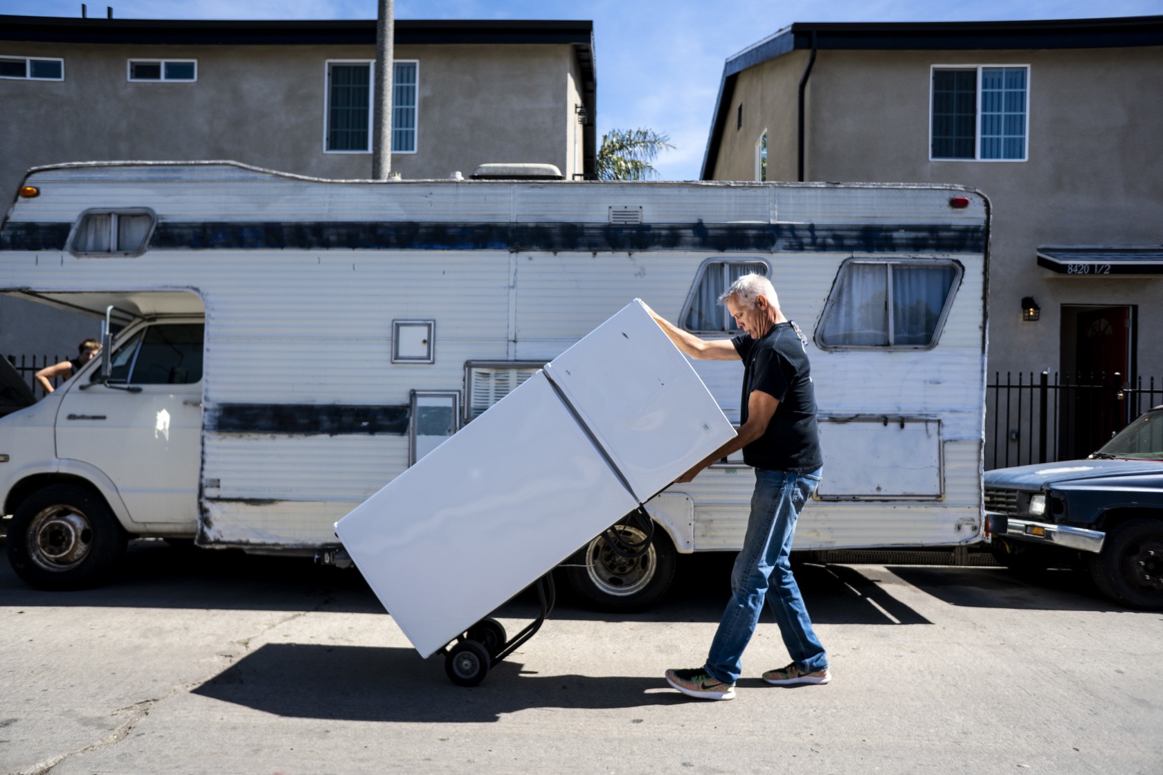 John Betz rolls a refrigerator down a street in South Los Angeles for a duplex he and his partner, Heidi Roberts, set up to house homeless people in this undated photo. (Credit: Kent Nishimura / Los Angeles Times)