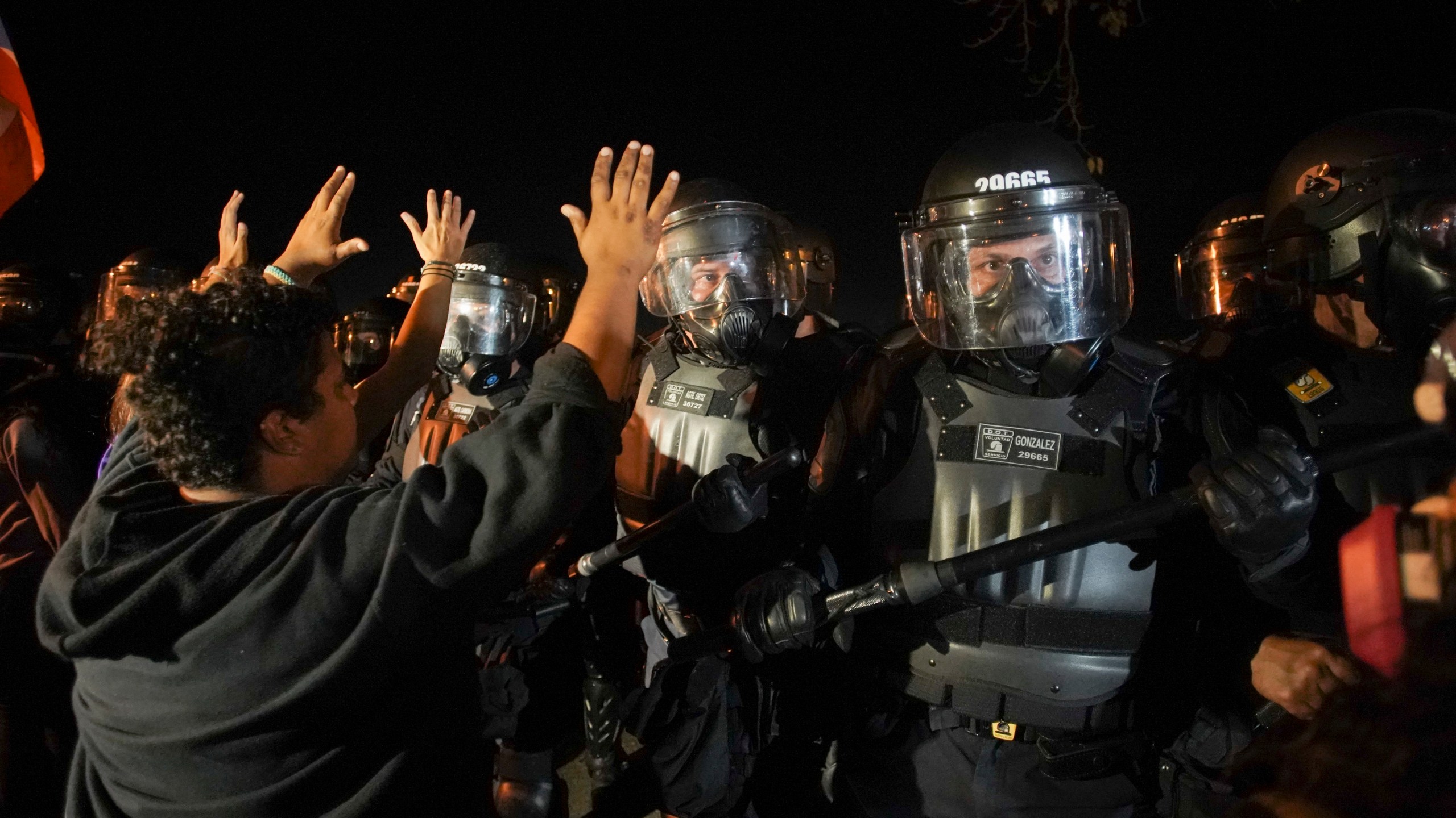 Protesters hold up their hands as they gather behind La Fortaleza to protest the newly designated governor, a member of the outgoing governor's New Progressive Party (PNP), as he was sworn in, in San Juan, Puerto Rico on Aug. 2, 2019. (Credit: ERIC ROJAS/AFP/Getty Images)