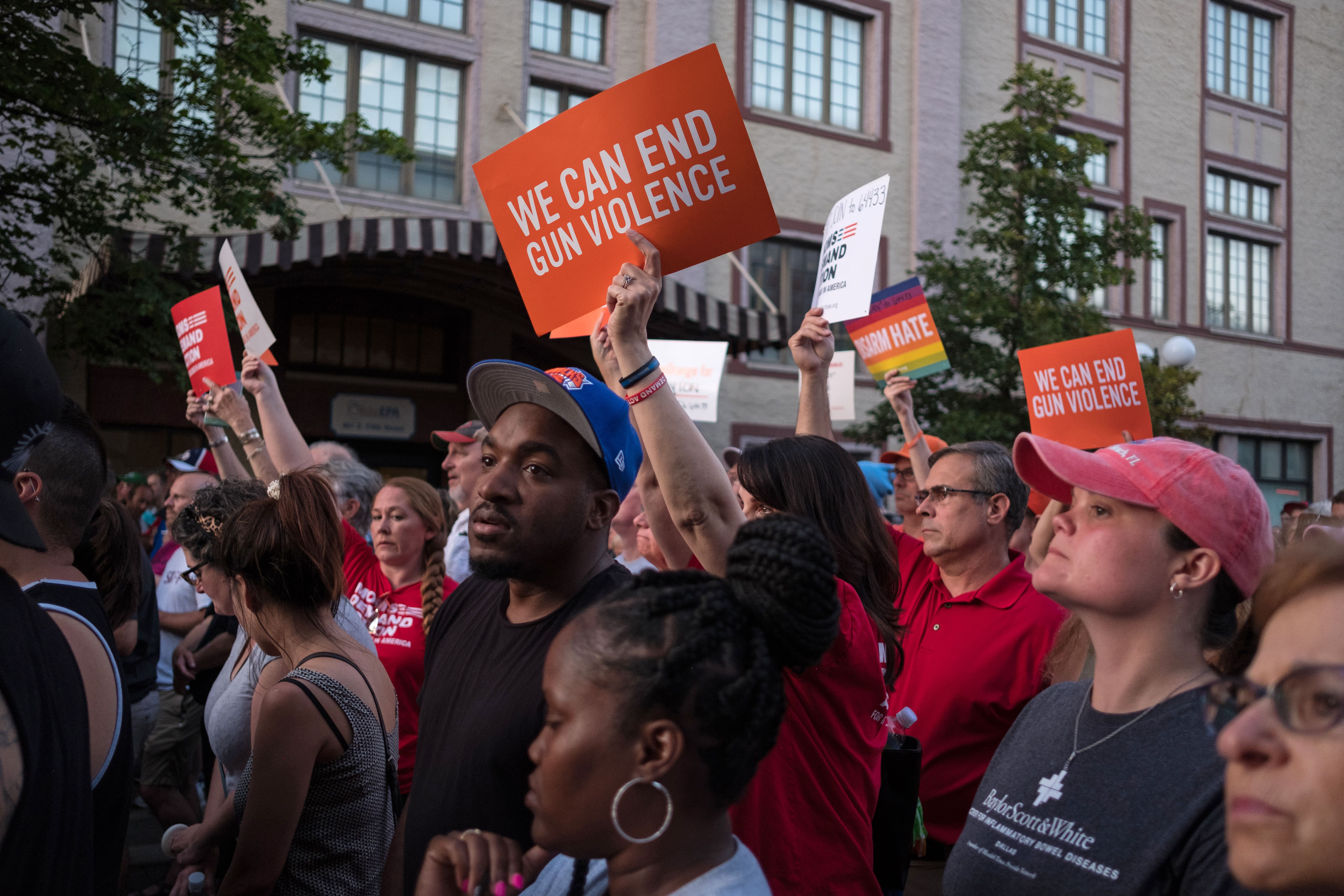 People hold signs as they take part of a candle lit vigil in honor of those who lost their lives or were wounded in a shooting in Dayton, Ohio on August 4, 2019. (Credit: MEGAN JELINGER/AFP/Getty Images)