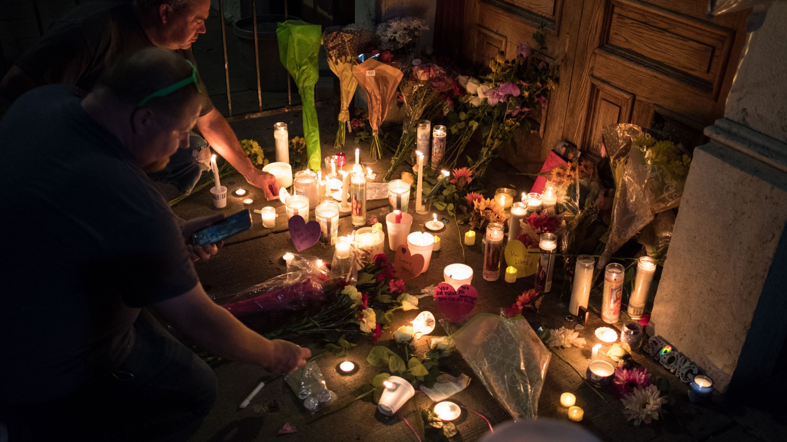 Two men light candles at a makeshift memorial as they take part of a candle lit vigil in honor of those who lost their lives or were wounded in a shooting in Dayton, Ohio on August 4, 2019. (Credit: MEGAN JELINGER/AFP/Getty Images)