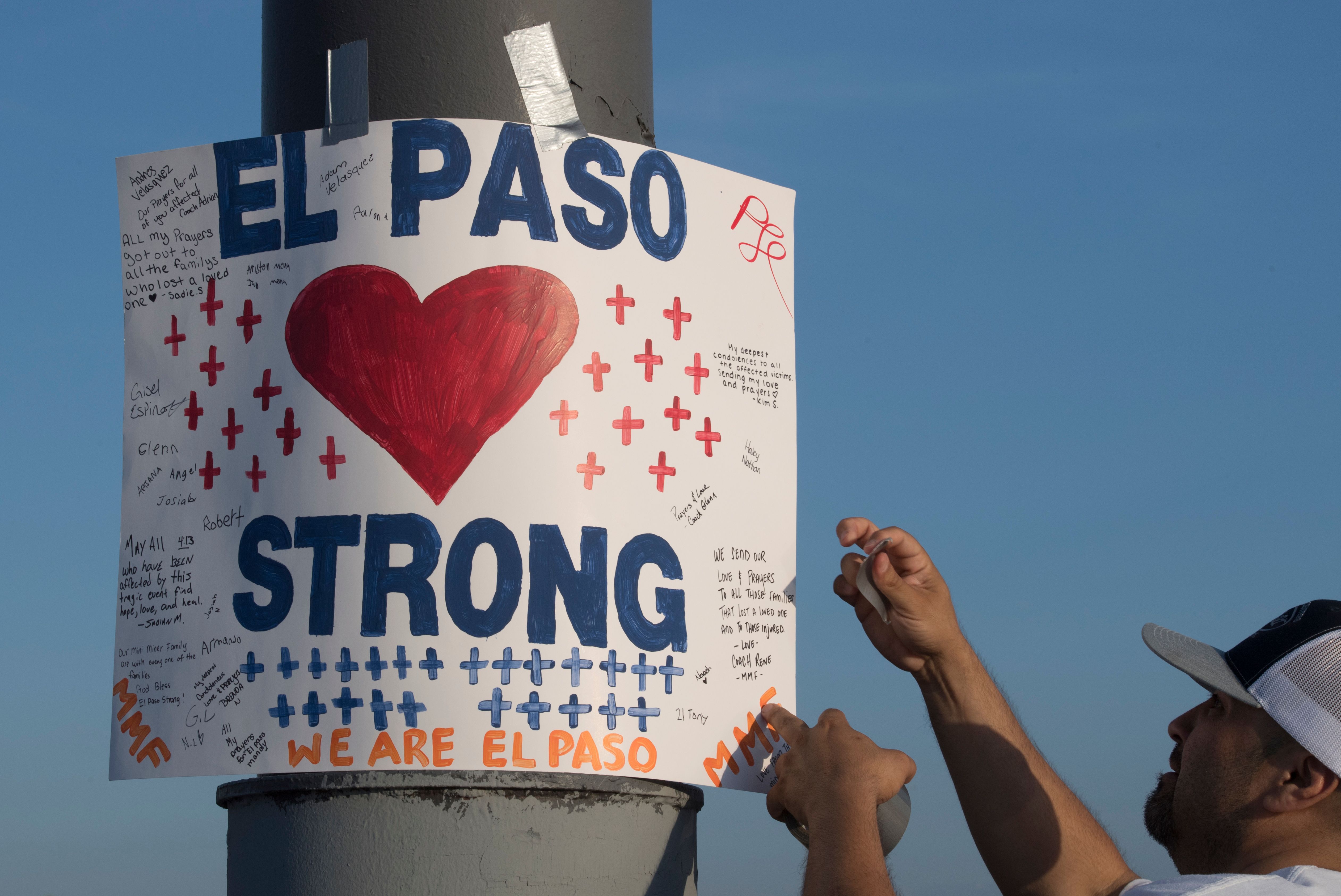 A man installs a 'El Paso Strong' sign at the makeshift memorial for victims of the shooting that left a total of 22 people dead at the Cielo Vista Mall Walmart in El Paso, Texas, on August 6, 2019. (Credit: MARK RALSTON/AFP/Getty Images)