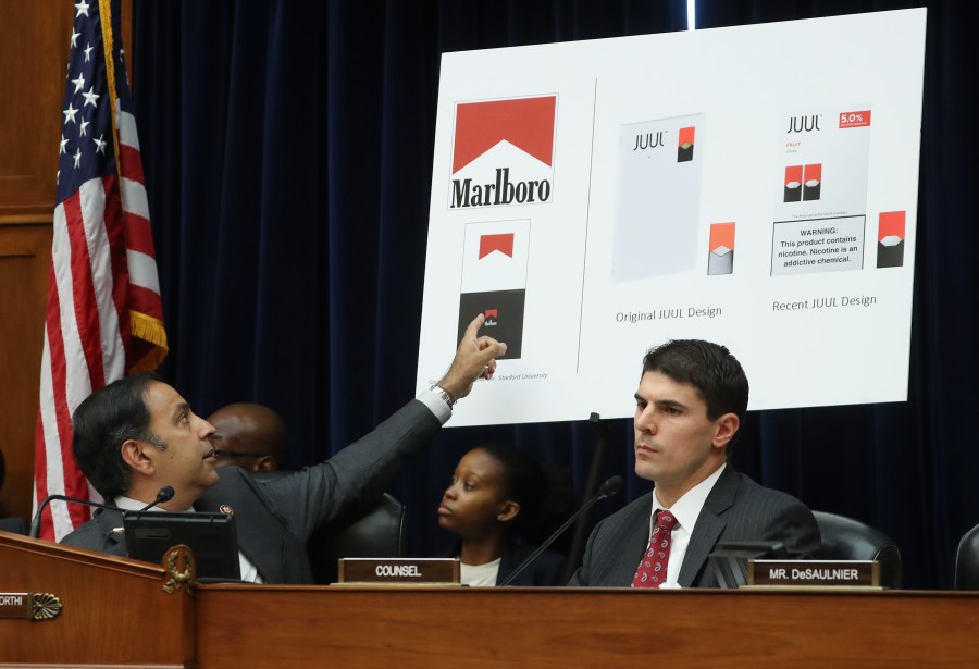 Chairman Raja Krishnamoorthi, left, points to a poster showing similarities between Marlboro cigarette ads and Juul vaping paraphernalia during a House Economic and Consumer Policy Subcommittee hearing on July 25, 2019. (Credit: Mark Wilson / Getty Images)