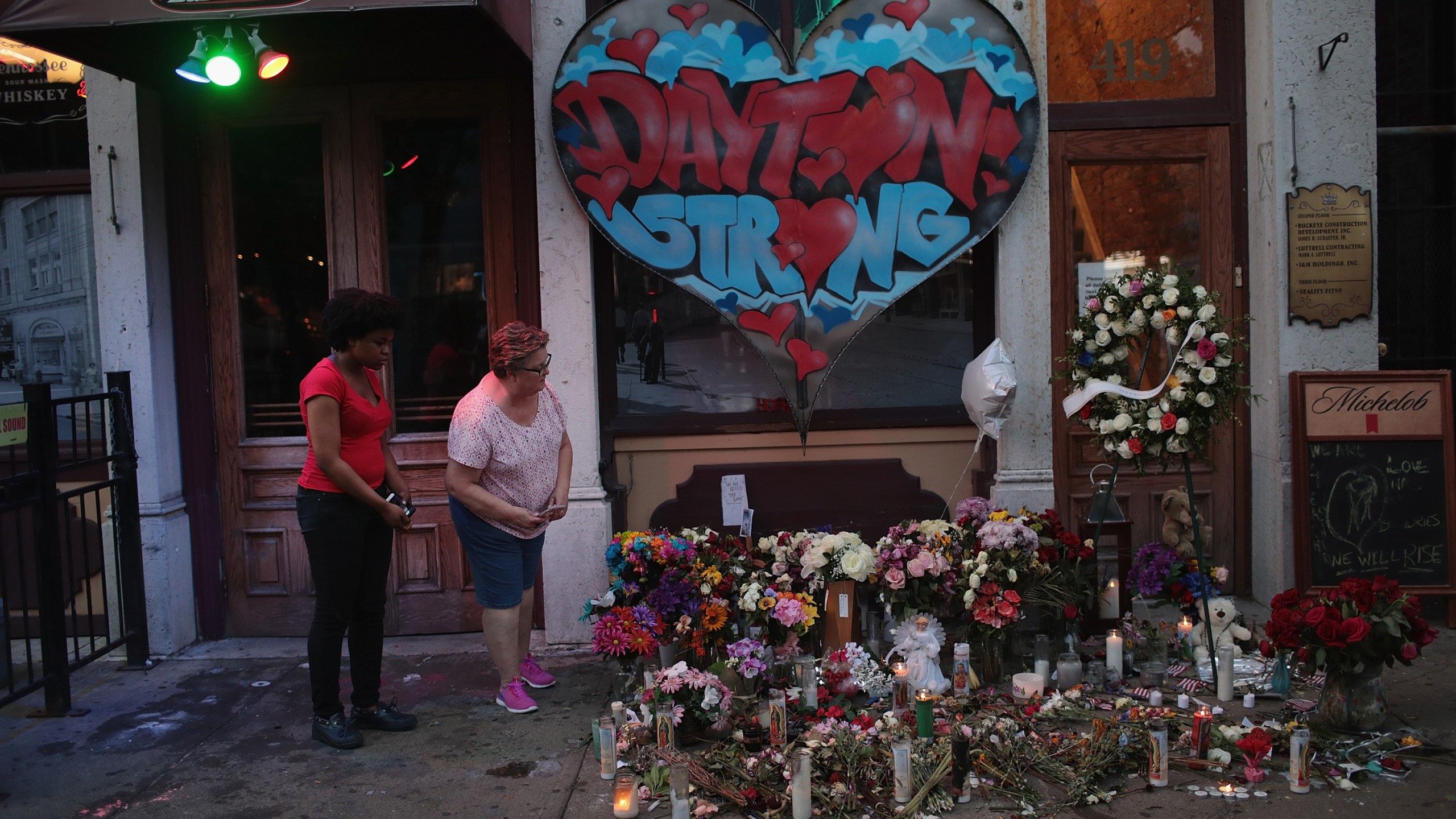 People look over a memorial to those killed in a mass shooting while the businesses along E. 5th Street in the Oregon District try to return to normal on Aug. 6, 2019, in Dayton, Ohio. (Credit: Scott Olson/ Getty Images)