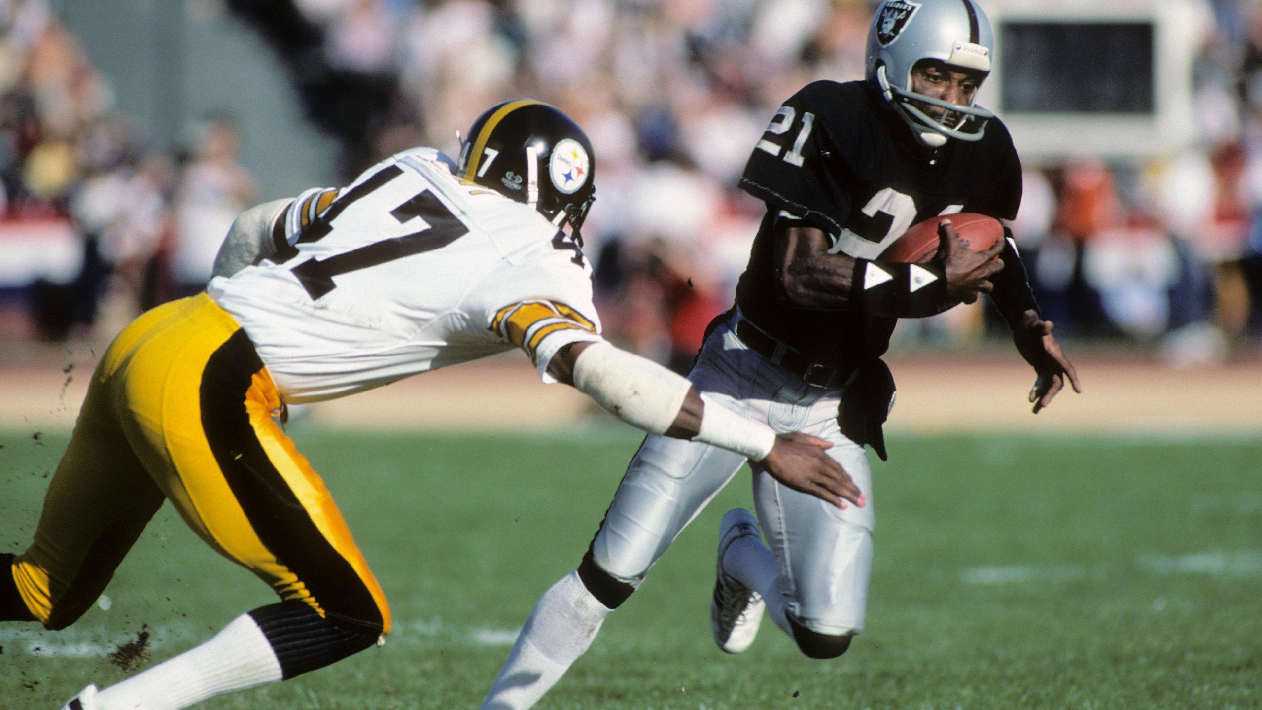 Cliff Branch #21 of the Los Angeles Raiders runs the ball against Mel Blount #47 of the Pittsburgh Steelers during the AFC Divisional playoff game at the Los Angeles Memorial Coliseum on Jan. 1, 1984, in Los Angeles. (Credit: George Rose/Getty Images)