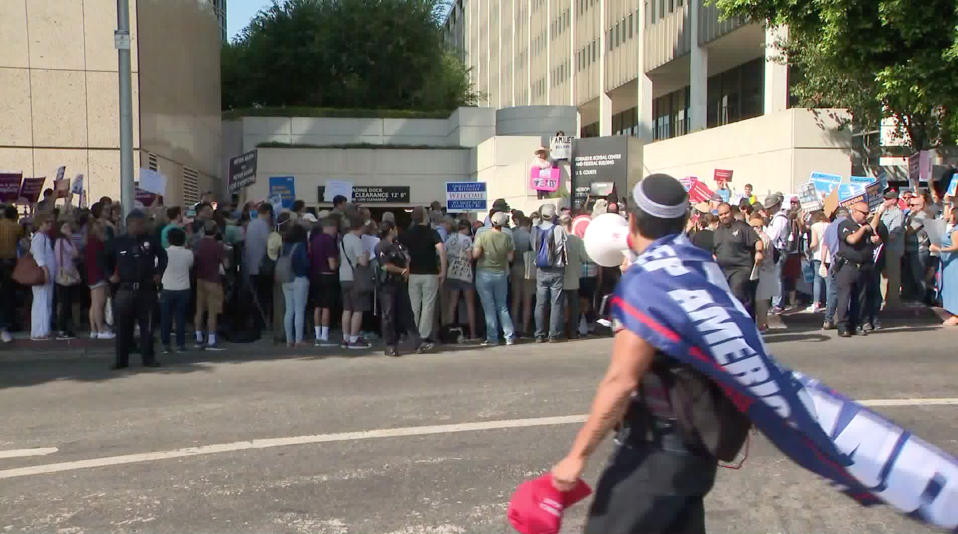 A man clad in Donald Trump gear yells "shame on all of you" to immigration rights advocates at a "Close the Camp" rally outside the Metropolitan Detention Center on Aug. 11, 2019. (Credit: KTLA)