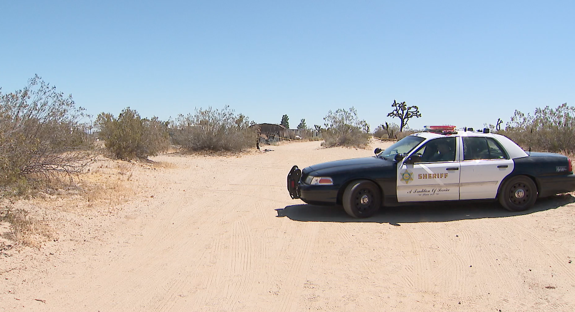 A Los Angeles County Sheriff's Department vehicle is seen near a cordoned-off area along a dirt road in the Palmdale area on Aug. 11, 2019. (Credit: KTLA)