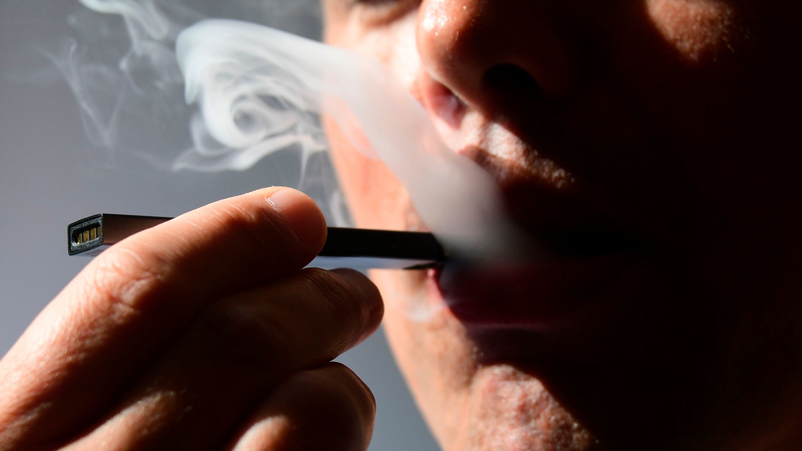 An illustration shows a man exhaling smoke from an electronic cigarette in Washington, DC on October 2, 2018. (Credit: EVA HAMBACH/AFP/Getty Images)