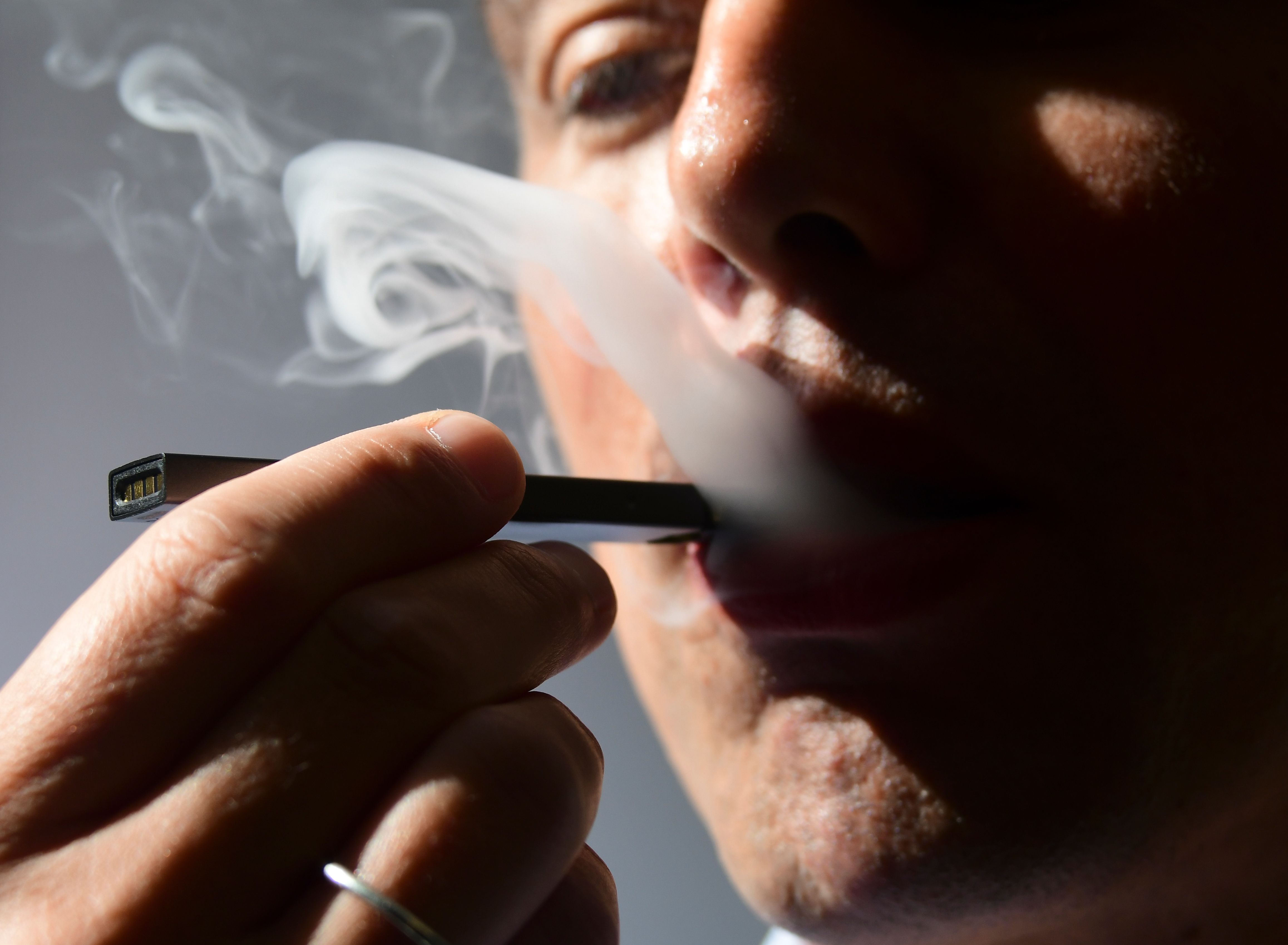 An illustration shows a man exhaling smoke from an electronic cigarette in Washington, DC on October 2, 2018. (Credit: EVA HAMBACH/AFP/Getty Images)