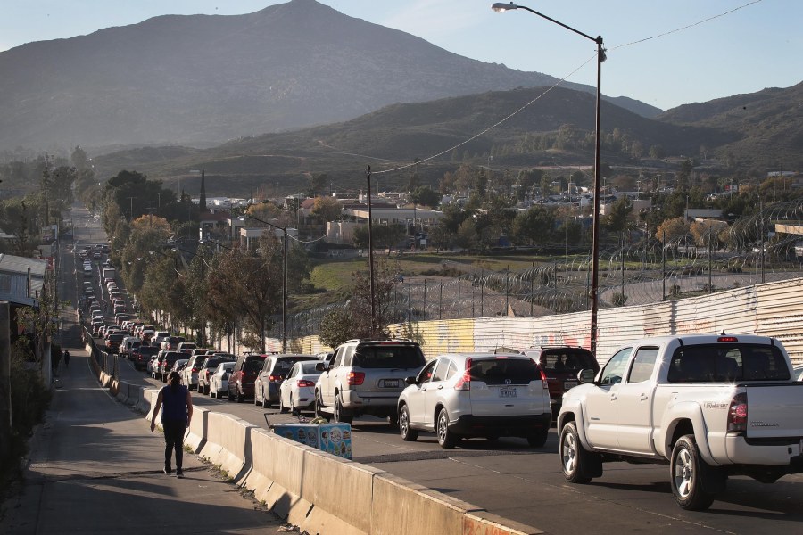 Motorists heading to the United States from Tecate, Mexico, wait along the U.S. border wall to pass through the port of entry on Jan. 27, 2019. (Credit: Scott Olson / Getty Images)