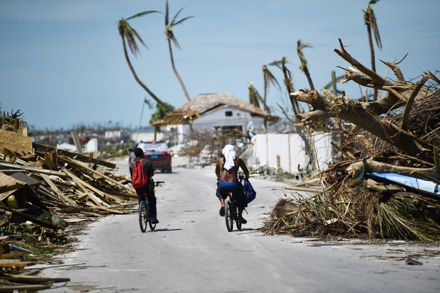 Residents pass damage caused by Hurricane Dorian on September 5, 2019, in Marsh Harbour, Great Abaco Island in the Bahamas. (Credit: BRENDAN SMIALOWSKI/AFP/Getty Images)