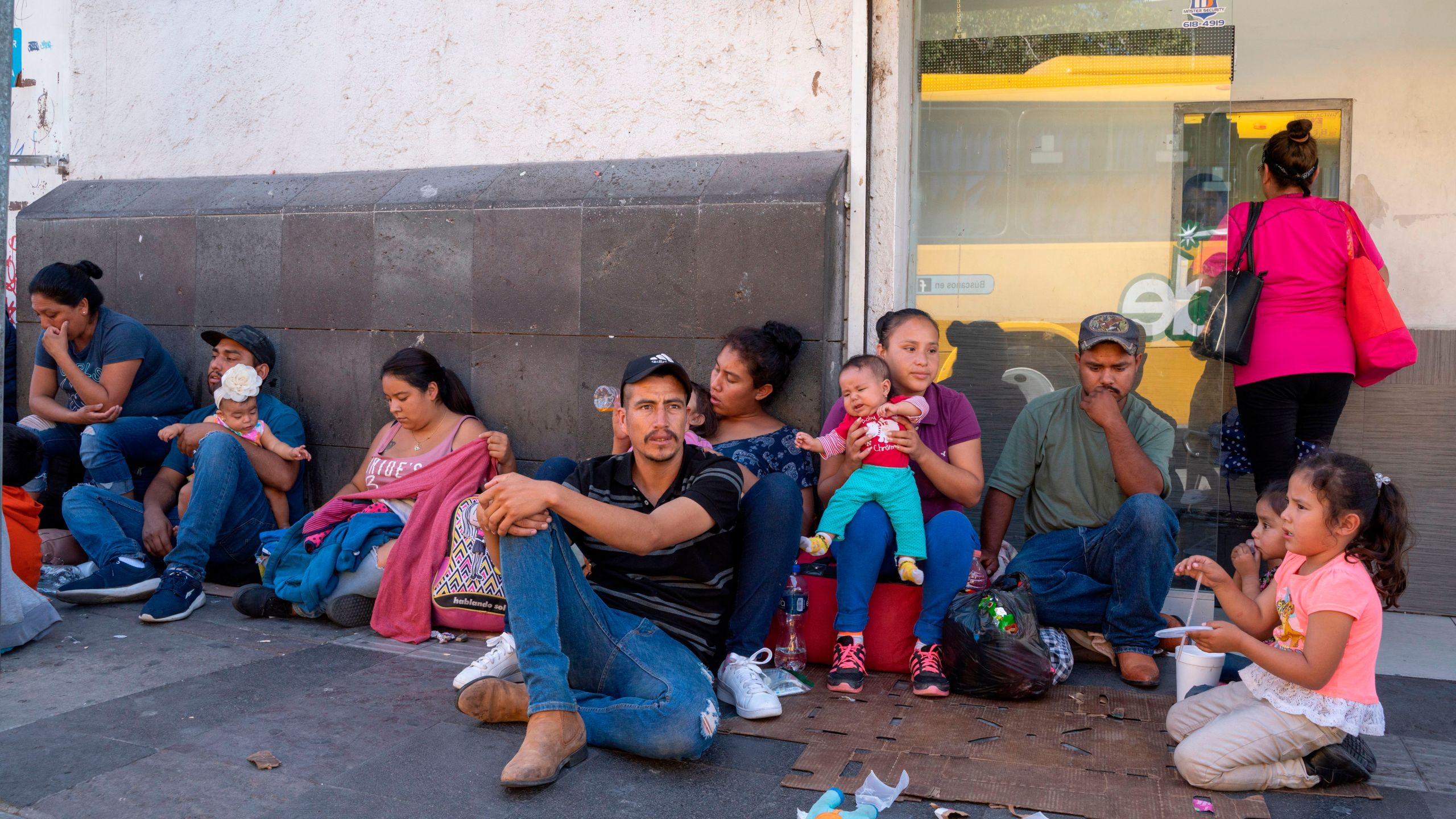 Migrants, mostly from Mexico, are pictured sitting on the ground waiting near the Paso del Norte Bridge at the Mexico-US border, in Ciudad Juarez, Mexico, on September 12, 2019. (Credit: PAUL RATJE/AFP/Getty Images)